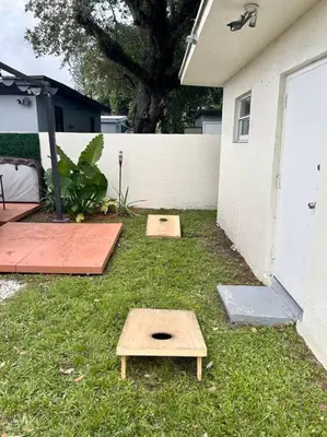 two wooden platforms in the grass next to a house at Modern Home w Jacuzzi Near Wynwood-Design District-MIA Airport in Miami