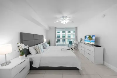 a white bedroom with a large bed and a television at 36th-Floor Ocean View Brickell - Free Parking in Miami
