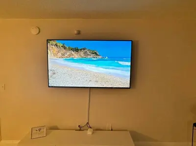 a flat screen tv hanging on a wall with a beach at 36th-Floor Ocean View Brickell - Free Parking in Miami