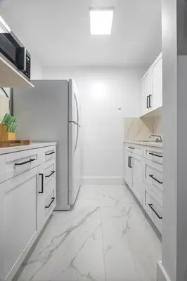 a white kitchen with white cabinets and a refrigerator at Nice,Stylish King Bed Studio in Miami Gardens