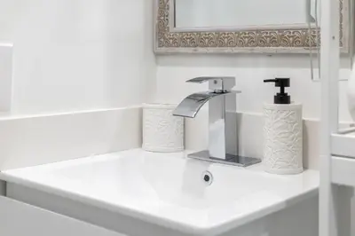 a white bathroom with a sink with a faucet at Nice,Stylish King Bed Studio in Miami Gardens