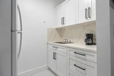 a white kitchen with a sink and a refrigerator at Nice,Stylish King Bed Studio in Miami Gardens