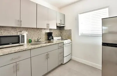 a white kitchen with a sink and a microwave at Krymwood Flats Wynwood in Miami