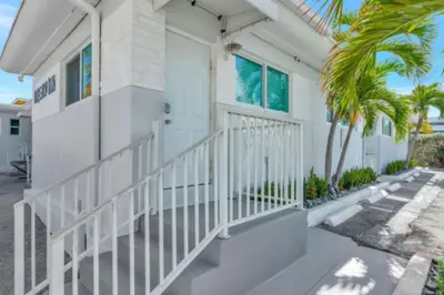 a white house with a white door and a palm tree at Hollywood Beach Escapade Studio with Free Parking in Hollywood