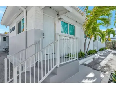 a white house with a white door and a palm tree at Coastal Retreat ONLY 1 block from the beach in Hollywood