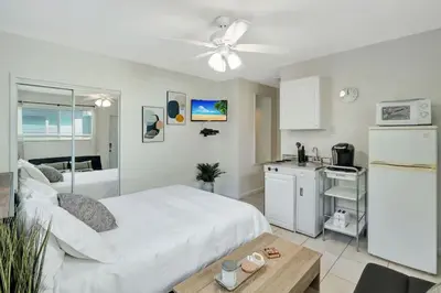 a bedroom with a white bed and a kitchen at Sunny Serenity Hollywood Studio Getaway in Hollywood