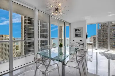 a dining room with a glass table and chairs and windows at Large Suites in Hotel W with bay views in Miami