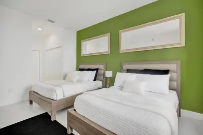 two beds in a room with a green wall at Penthouse Sky Suite - 2BDR2BTH - Private Rooftop Terrace in Hallandale Beach