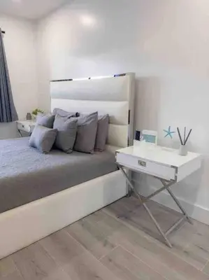 a white bedroom with a bed and a side table at Beach Getaway in Hollywood