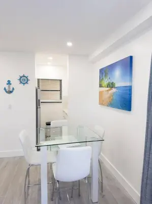 a dining room with a glass table and white chairs at Beach Getaway in Hollywood