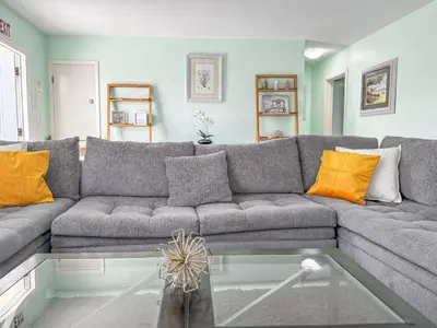 a living room with a gray couch with orange pillows at Sunrise Delight 2 min walk to Beach Essentials in Hollywood