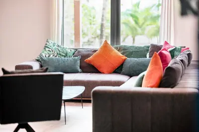 a living room with a brown couch with colorful pillows at The Netherland 2A I Ocean Drive I MIAMI BEACH OCEAN RENTAL in Miami Beach