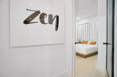 a white room with a bed and a sign on a wall at NEW Bali Resort Style Villa with Vast Pool & Jacuzzi and Outdoor Grilling in Miami