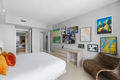 a bedroom with a bed and a desk and pictures on the wall at Seaside Splendor! Modern Condo with Ocean View in Hollywood