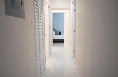 a hallway with white walls and a room with a bed at Cozy Central Stay Airport, KingBed, Fenced Parking - Little Havana Near Airport, Wynwood, Calle 8 Brickell, Coral Gables and more in Miami