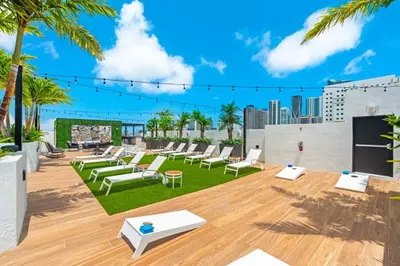 a rooftop patio with lounge chairs and palm trees at The Logan I in Miami