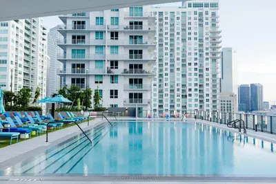 a large swimming pool with blue chairs and a tall building at The Bayfront VII in Miami