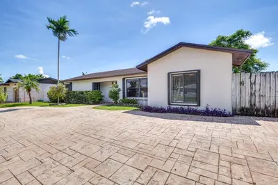 a house with a fence and a paver driveway at Pet-Friendly Home with Yard about 3 Mi to Zoo Miami! in Cutler Ridge