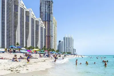 a beach with many people in the water and buildings at Modern 1 BR Condo, Steps from Beach, Free Parking! in Sunny Isles Beach