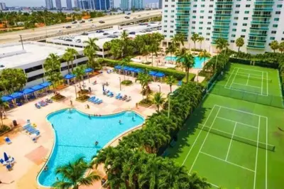 an aerial view of a resort with a tennis court at Modern 1 BR Condo, Steps from Beach, Free Parking! in Sunny Isles Beach