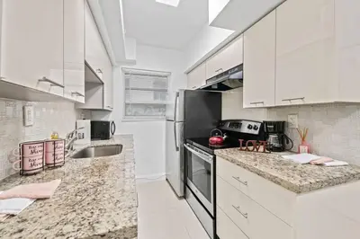 a kitchen with white cabinets and granite counter tops at Escape 2 Beach, Ocean Dr Deco Apt with 2 Queen beds in Miami Beach