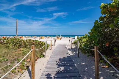a boardwalk leading to a beach with people on it at Escape 2 Beach, Ocean Dr Deco Apt with 2 Queen beds in Miami Beach