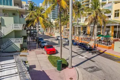 a red car parked in a parking lot with palm trees at Easy Ocean Dr Beach, 2 Queenbeds in Miami Beach