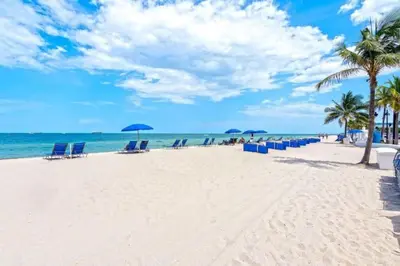 a beach with chairs and umbrellas and the ocean at Renovated Intercoastal 2Bdrm 1 bath condo Walk to Beach in Fort Lauderdale