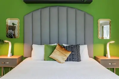 a bedroom with a bed with green walls and mirrors at Claremont Hotel in Miami Beach