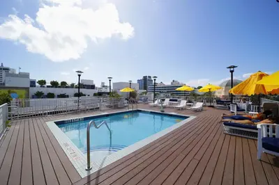a swimming pool on a deck with chairs and umbrellas at Claremont Hotel in Miami Beach