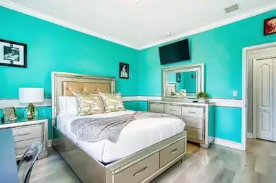 a blue bedroom with a bed and a mirror at Luxury Tropical Living , 4BR w Backyard Pool Oasis in Hialeah