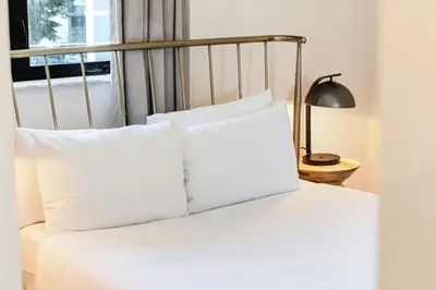 a bed with white pillows and a lamp and a window at Roami at The Palace in Miami