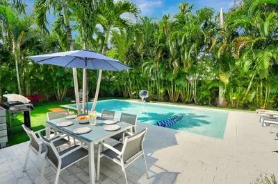 a table with an umbrella next to a swimming pool at Zen Den - Heated Pool, Work Friendly, Near Beach in Fort Lauderdale