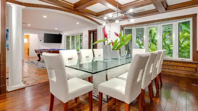 a dining room with a glass table and white chairs at 5mins to Beach • Pool Hot Tub • Billiards Coral Ridge Getaway by AvantStay in Fort Lauderdale