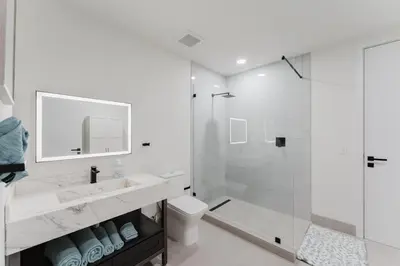 a white bathroom with a shower and a toilet at Modern 2BR, Family-Friendly in FLL, Near Beach! in Fort Lauderdale