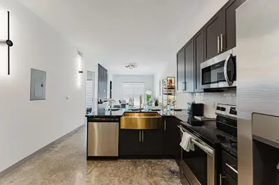 a kitchen with black cabinets and a gold sink at Prime 2BR Near FLL Airport, Dania Beach & Pointe in Fort Lauderdale