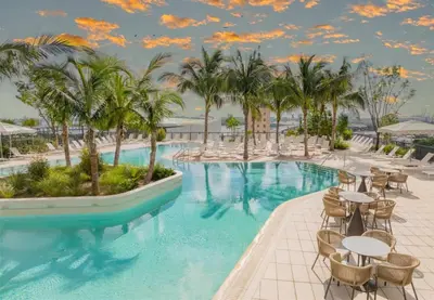 a resort pool with tables and chairs and palm trees at Spectacular Apartment with Pool & Gym in Miami