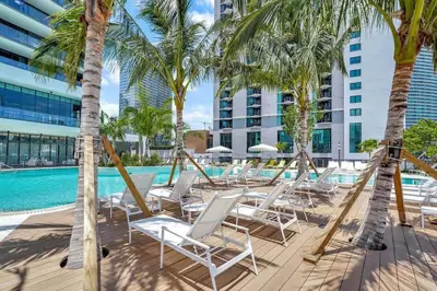 a row of chairs and palm trees next to a swimming pool at Chic Downtown - City Views Gym & Pool in Miami