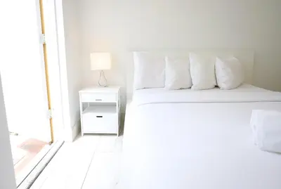 a white bedroom with a bed with white pillows at 3 Minute Walk to Miami Beach Family and Pet Friendly Apartment in Miami Beach