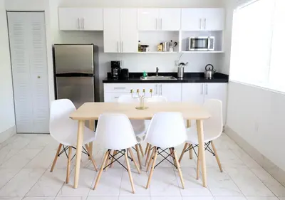 a kitchen with a wooden table and white chairs at 3 Minute Walk to Miami Beach Family and Pet Friendly Apartment in Miami Beach
