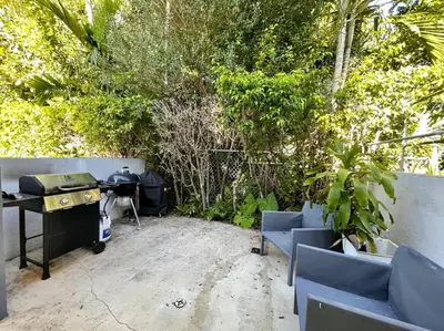 a patio with a desk and chairs and trees at 2Bdrm 1Bath Newly Renovated Condo - Walk to the Beach! in Fort Lauderdale