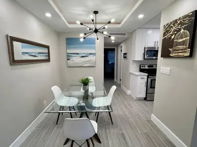 a dining room with a glass table and white chairs at 2Bdrm 1Bath Newly Renovated Condo - Walk to the Beach! in Fort Lauderdale