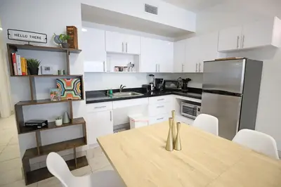a kitchen with a wooden table and white cabinets at 3 Bedroom 3 Bathroom Miami Beach Apartment in Miami Beach