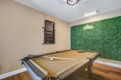 a pool table in a room with a green wall at 11 Mi to South Beach Home with Screened Porch! in Miami