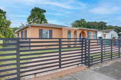 a house with a fence in front of it at 11 Mi to South Beach Home with Screened Porch! in Miami