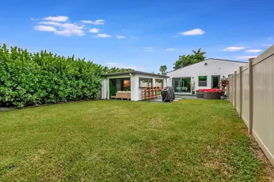 a backyard of a house with a large yard at Lovely 2BR 2BA Modern Flat with Vibrant Backyard in Fort Lauderdale