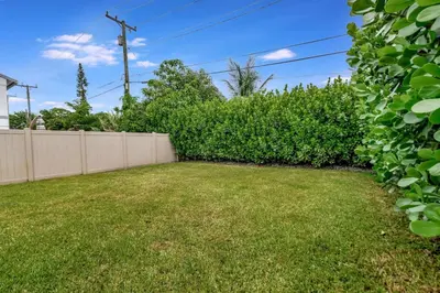a yard with a fence and a hedge at Lovely 2BR 2BA Modern Flat with Vibrant Backyard in Fort Lauderdale