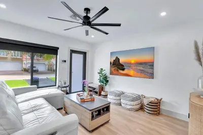 a living room with a white couch and a ceiling fan at Lovely 2BR 2BA Modern Flat with Vibrant Backyard in Fort Lauderdale