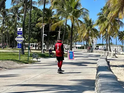 a man riding a skateboard down a sidewalk at Ocean Drive Steps to Sea in South Beach with Free Parking in Miami Beach