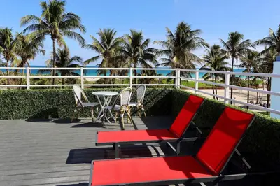 a patio with chairs and a table and palm trees at Ocean Drive Oasis in Art Deco District of South Beach in Miami Beach